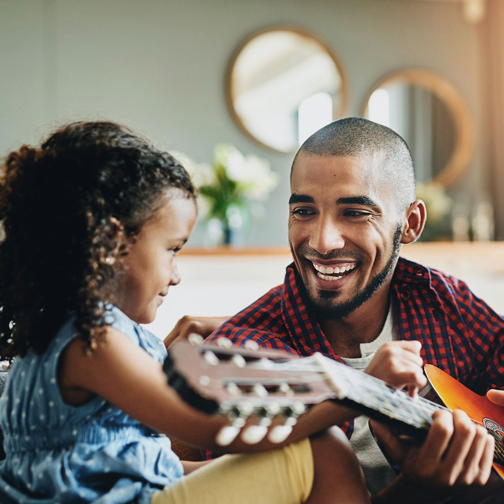 Mann mit Gitarre lächelt Kind an