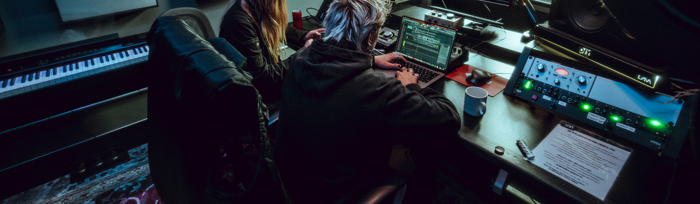 zwei Personen sitzen im Studio in einer dunklen Atmosphäre