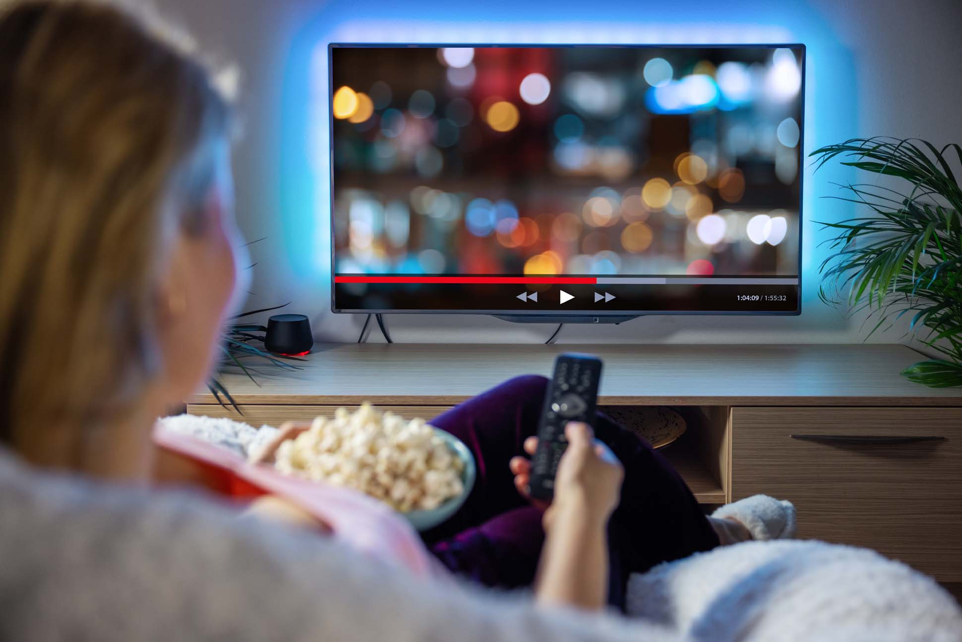 Frau sitzt auf der Coach mit Popcorn und schaut Tv