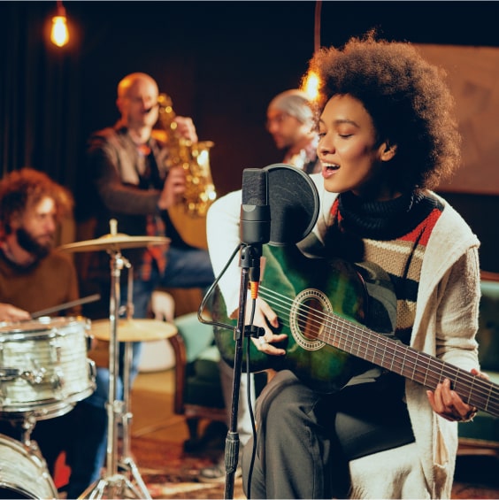 Sängerin spielt Gitarre und wird von einer Band begleitet.