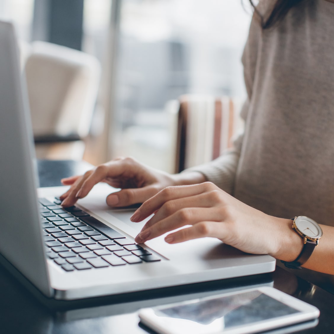 Frau sitzt an Tisch mit Laptop und tippt