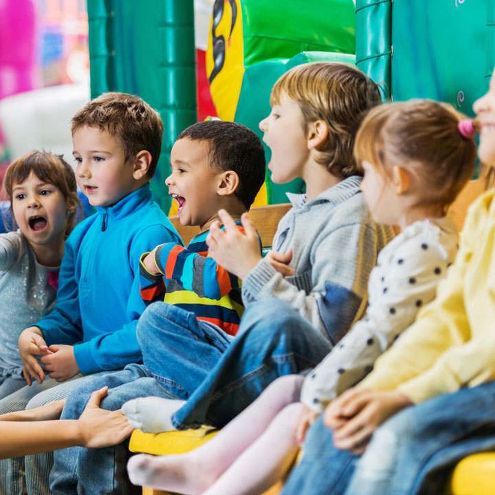 Junge Kinder sitzen zusammen und freuen sich.