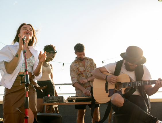 Eine Band aus vier Personen spielen unter freiem Himmel ein Konzert.