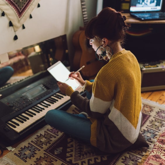 Eine Frau sitzt vor einem Keyboard mit einem iPad in der Hand.